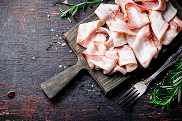 Canvas Print - Pieces of fresh bacon on a cutting board with spices. 