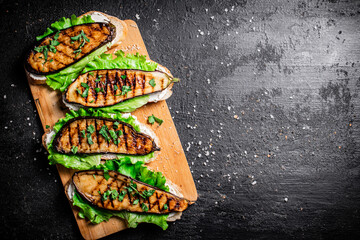 Canvas Print - Sandwich with grilled eggplant and lettuce on a wooden cutting board. 