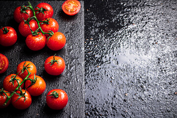 Wall Mural - Fresh tomatoes on a branch on a stone board.