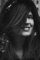 Wall Mural - Close up smiling lady with fairy lights in hair monochrome portrait picture. Closeup front view photography with blurry background. High quality photo for ads, travel blog, magazine, article