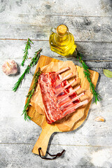 Canvas Print - Raw rack of lamb on a cutting board with oil and rosemary. 