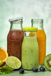 Green, orange and red smoothie in glass bottles.