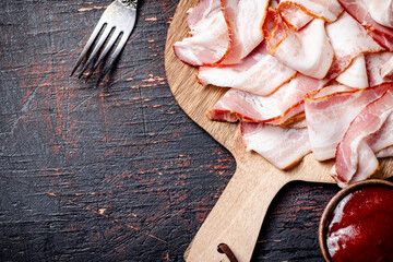 Canvas Print - Pieces of bacon on a cutting board with tomato sauce.