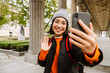 © Drobot Dean - Beautiful asian woman tourist taking selfie and waving during walk through the old city street