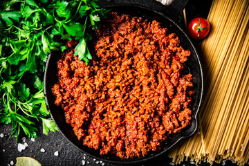 Poster - Bolognese sauce in a frying pan with pasta dry and parsley. 