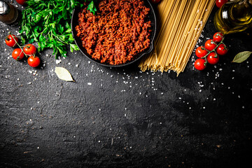 Wall Mural - Bolognese sauce in a frying pan with pasta dry and parsley. 