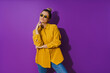 © blackday - Young  girl wearing yellow shirt and sunglasses showing disdain expression against purple background