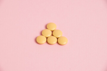 Wall Mural - Yellow vitamins in pills on a pink paper background. Concept of immunity support in spring.