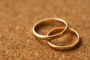Wall Mural - Two wedding rings on a cork table background with shallow DOF