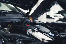 Close-up Shot Of Unrecognisable Man Wearing Black Glove Inspecting Car Engine And Interior Of Hood Of Car. Garage Work. Horizontal Indoor Shot. High Quality Photo
