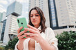 © Jose Calsina - Close up portrait of brunette caucasian girl watching news concentrated on a smartphone app. Serious young caucasian woman using a cellphone standing outdoors. High quality photo