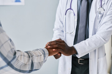 Wall Mural - Close up caring black doctor holding hands with female patient