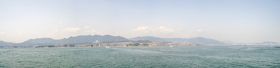 Beautiful panoramic landscape of Miyajima city with ferry boat from the island in Hiroshima prefecture.