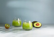 Avocado shake or smoothie, made with avocados and kiwi and Ice. Green Avocado smoothie and kiwi on a blue background. Selective focus. 