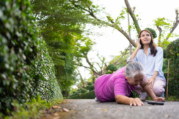 Asian senior woman fell down on lying floor because faint and limb weakness and pain from accident and woman came to help support and call emergency. Concept of old elderly insurance and health care