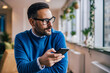 © bnenin - Side view of a businessman, using a mobile phone while sitting at the office.
