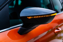 Close-up View Of Rear Of The Side Mirror Of Modern Orange And Black Car With Orange Led Turn Signal Light