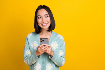 Wall Mural - Photo of lovely nice positive woman with bob hairdo dressed blue pullover hold phone look empty space isolated on yellow color background