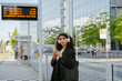 © Drobot Dean - Young businesswoman in headphones using cellphone on city street