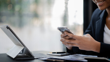 Close up american woman holding smartphone, she is using smartphone browsing social media and chatting with friends on online messaging app. The concept of using a smartphone.