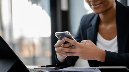 Close up american woman holding smartphone, she is using smartphone browsing social media and chatting with friends on online messaging app. The concept of using a smartphone.