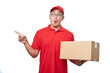 © Reza - Young handsome asian delivery man holding delivery package shocked while pointing with hand and finger to the left side