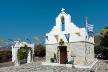 Small Church With Flower Wealth And Flags In Parikia, Paros, Cyclades, Greece