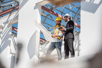 teamwork men in construction site, two civil engineer in safety helmet hard hat using digital tablet