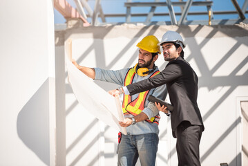 Teamwork men in construction site, Two civil engineer in safety helmet hard hat using digital tablet and blueprint working while standing at factory.