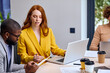 © Roman - Group of young business people collaborating on project in office, using laptop. Nice lady work on laptop while afro american guy in suit share opinion and discuss business idea, strategy