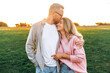 © Kateryna - Loving happy couple of Caucasian ethnicity, stylishly dressed, are walking outdoors in a park at sunset, tenderness hugging each other, smiling, man gently kisses his woman on the forehead