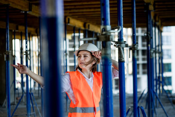 Wall Mural - Confident Female builder checks fastenings on a monolithic structure. Construction concept