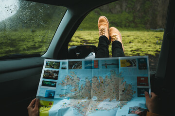 Woman traveling with.a car and looking for the right way on the map