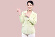 Cheerful excited young Asian woman pointing finger to side with copy space standing over isolated on pink background. Advertisement presenting concept.