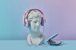 Antique statue in pink headphones and CD player.