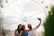 Friends Taking Selfie Against Ferris Wheel