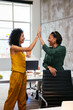 © BONNINSTUDIO/Stocksy - Positive businesswomen giving high five in office