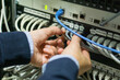 © ACALU Studio/Stocksy - Hands connecting cables in a server rack