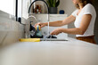 © Guille Faingold/Stocksy - Woman washing cutlery at home.