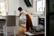 © Guille Faingold/Stocksy - Woman doing housework in kitchen.