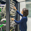 © ACALU Studio/Stocksy - Woman professional IT working in a communications rack