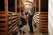© AD Astra Team/Stocksy - Two farmers are standing in a stable on a farm with a sheep