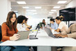 © Pedro Merino/Stocksy - Coworkers working on devices in a meeting room in an office