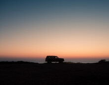 4x4 Car Silhouette Driving On Wild Coast Scenery At Sunset