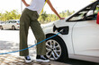 © BONNINSTUDIO/Stocksy - Crop woman standing near charging vehicle