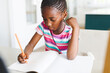 © Wavebreak Media - African american girl sitting at table and doing homework