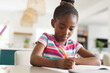© Wavebreak Media - African american girl sitting at table and doing homework