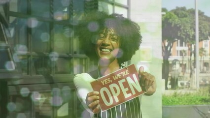 Wall Mural - Animation of portrait of african american female shop assistant with open sign over spots