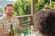 © Jordana Sheara/Stocksy - Man talking with friends and drinking wine at an outdoor dinner party
