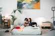 © Studio Marmellata/Stocksy - Happy young diverse ladies talking on bed at home